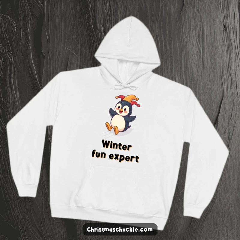 Funny penguin clown hoodie showing a cheerful penguin sliding down a festive hill with a clown nose, perfect for warmth.