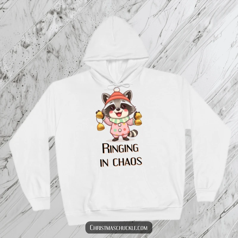 Funny hoodie featuring a cheerful raccoon in a clown outfit juggling festive jingle bells, bringing holiday spirit.