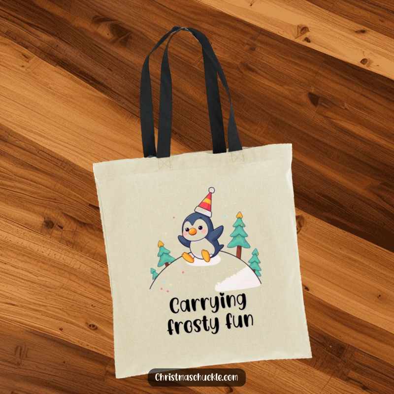 Funny tote bag featuring a cheerful penguin with a clown nose, joyfully sliding down a festive hill, perfect for winter outings.